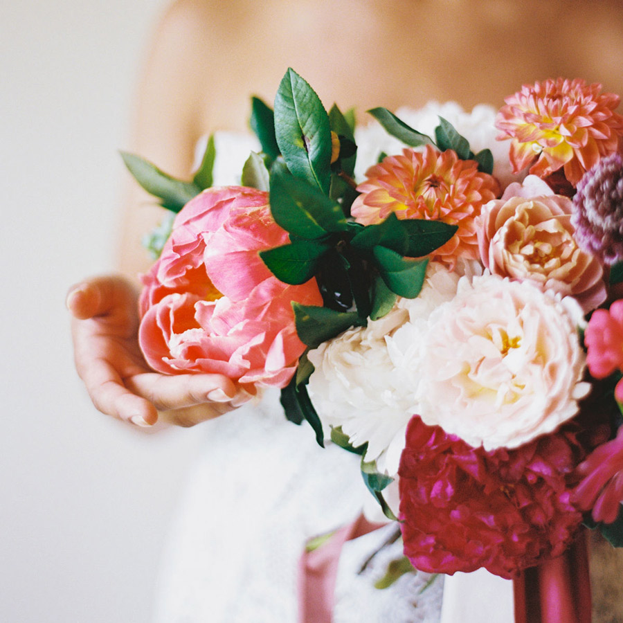 lose up of woman holding a bouquet of various colored flowers.