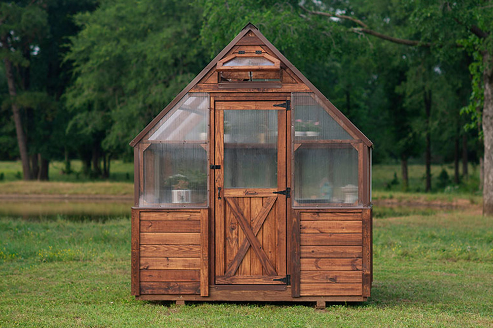 Exterior view of a 8x8 Yoderbilt Legacy Greenhouse with brown stain. The single door is closed.