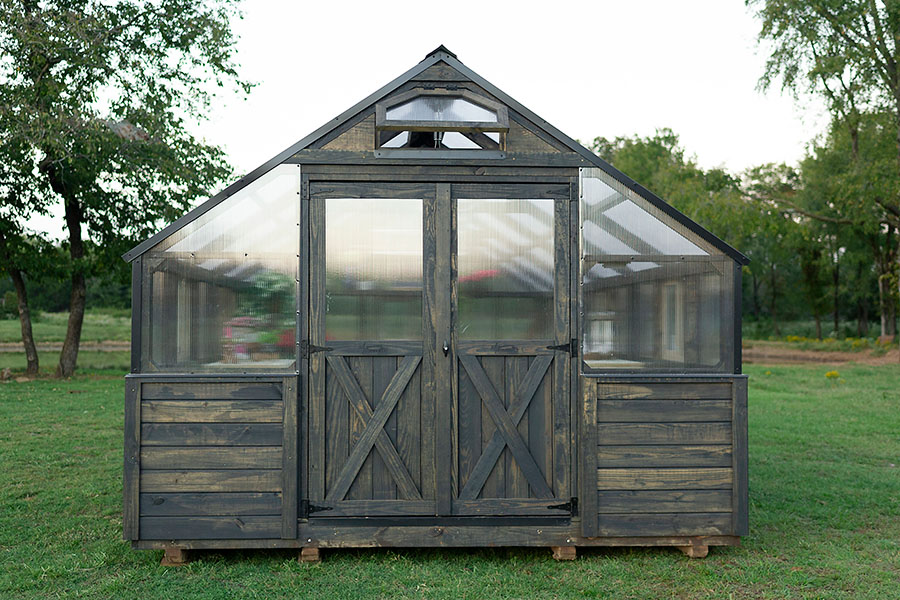 Front view of a 12x24 Yoderbilt Legacy Greenhouse with gray stain. Double doors are closed.