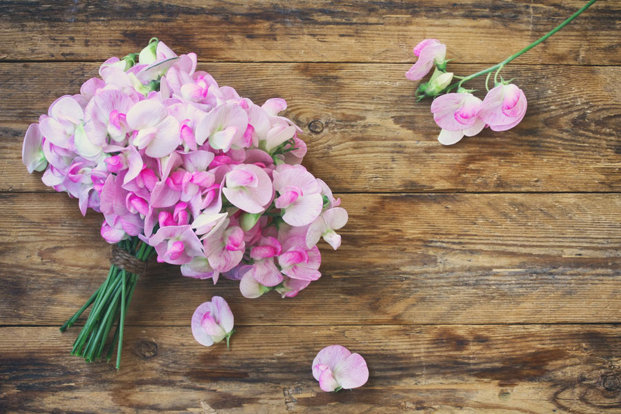 Bouquet of bright pink flowers and one flower separated sitting on a wooden table.
