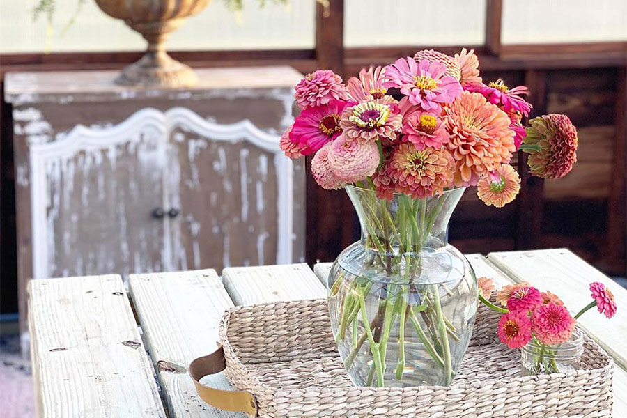 Close up of a vase of colorful flowers on a wooden table inside a Yoderbilt Greenhouse.