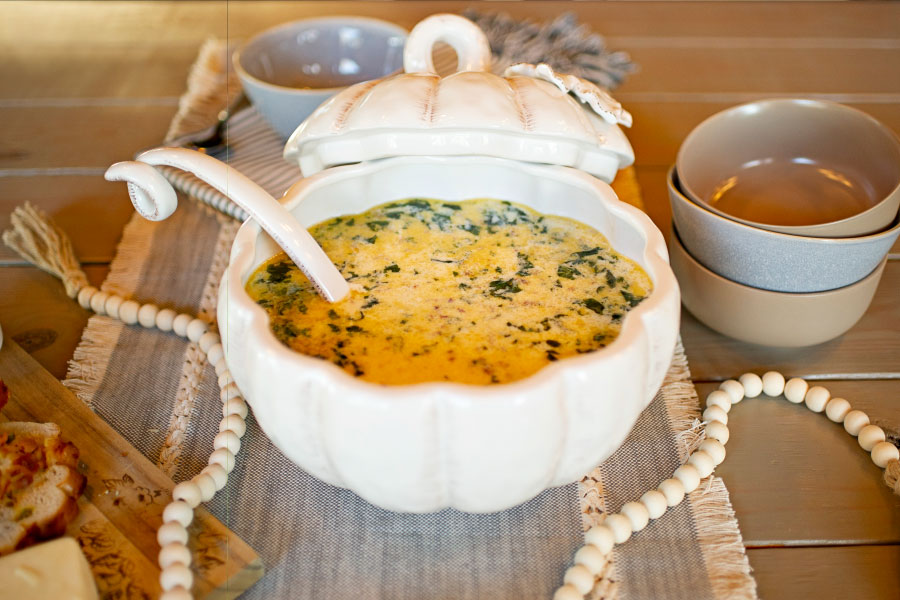 Soup inside a white bowl on a wooden table.