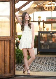 Teenage girl with white romper with her right arm posed behind her head