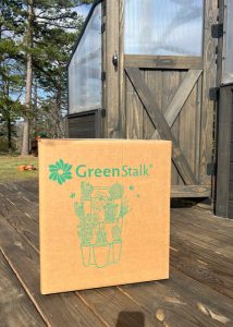 A GreenStalk® Box sitting outside of a Yoderbilt Greenhouse.