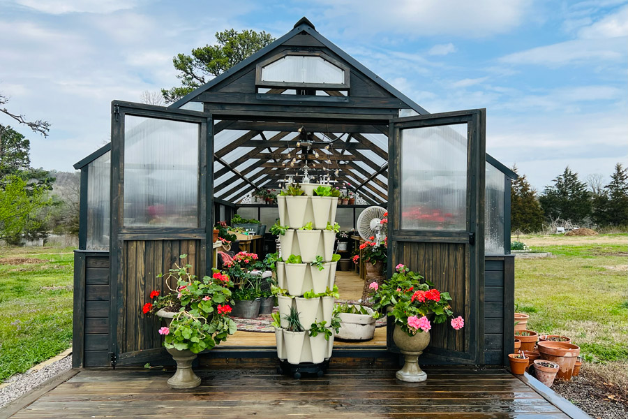 A grow tower placed in front of a Yoderbilt Greenhouse.