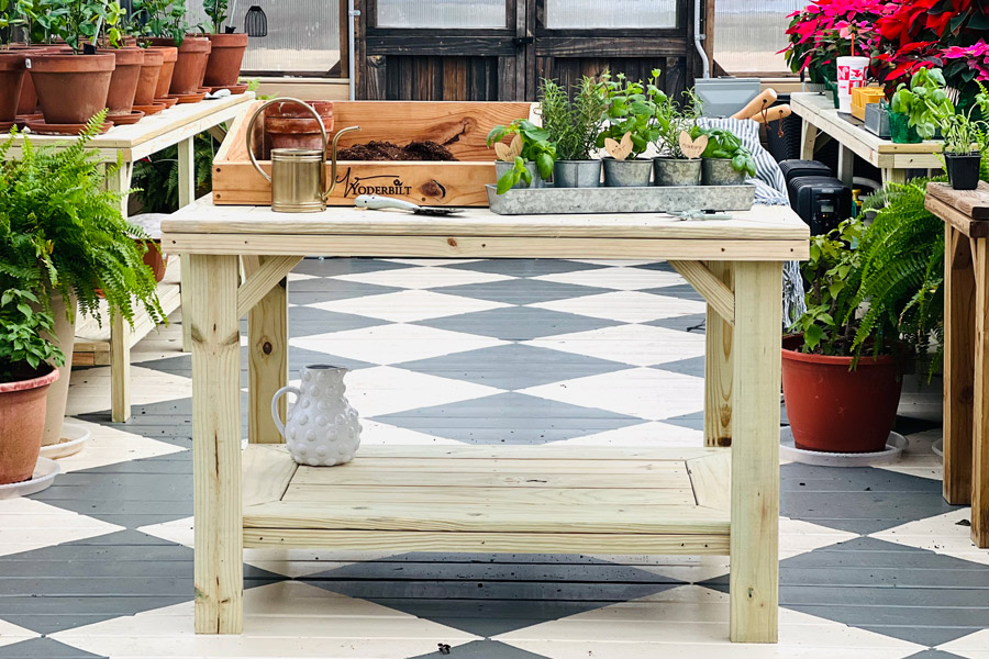 A Yoderbilt gardening table with gardening supplies placed on top.