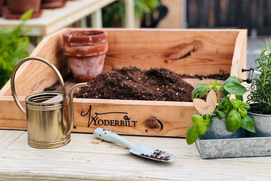 A wooden box with Yoderbilt branded on it and gardening tools.