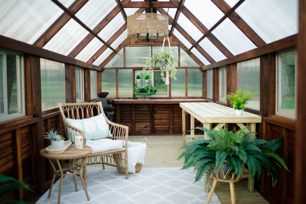 Inside of a Yoderbilt Greenhouse with a gardening table, hanging plant, chair and table