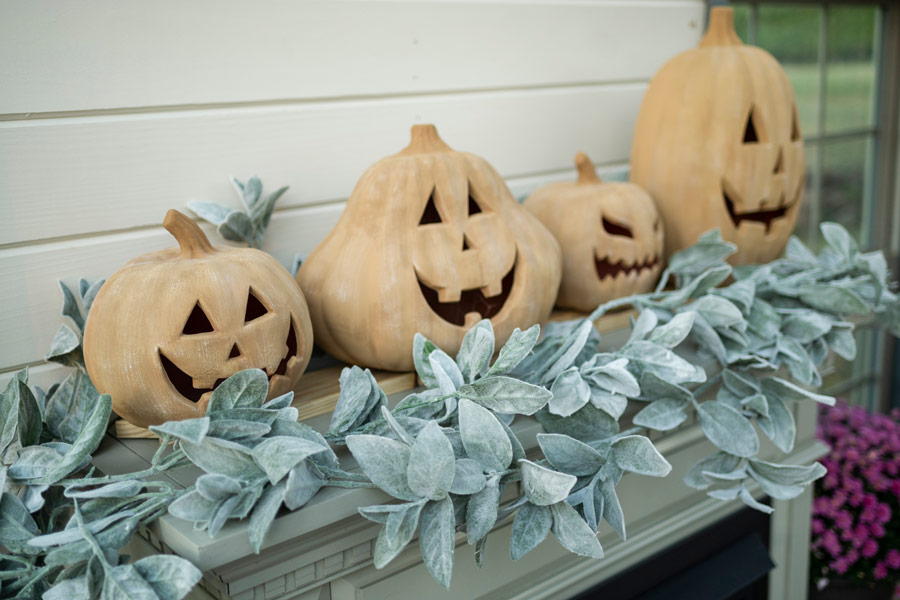 Four stylized terra cotta pumpkins sitting on a fireplace inside of Angela Yoder's Yoderbilt greenhouse