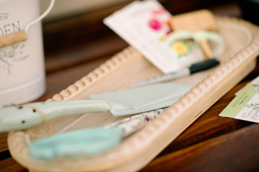 A tray with a gardening tool, a packet of seeds, and a sharpie laying on top of if