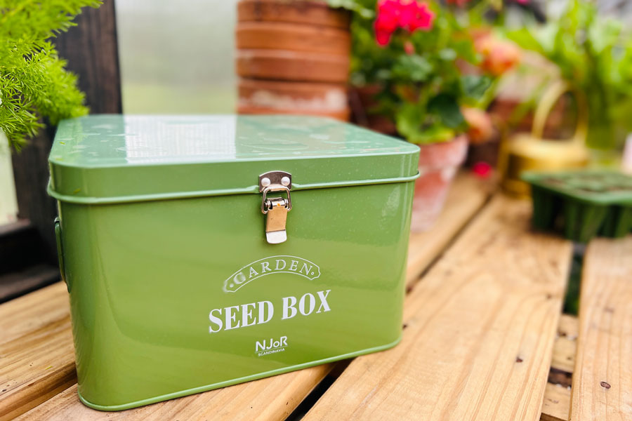 A green seed box on top of a gardening table in a Yoderbilt Greenhouse